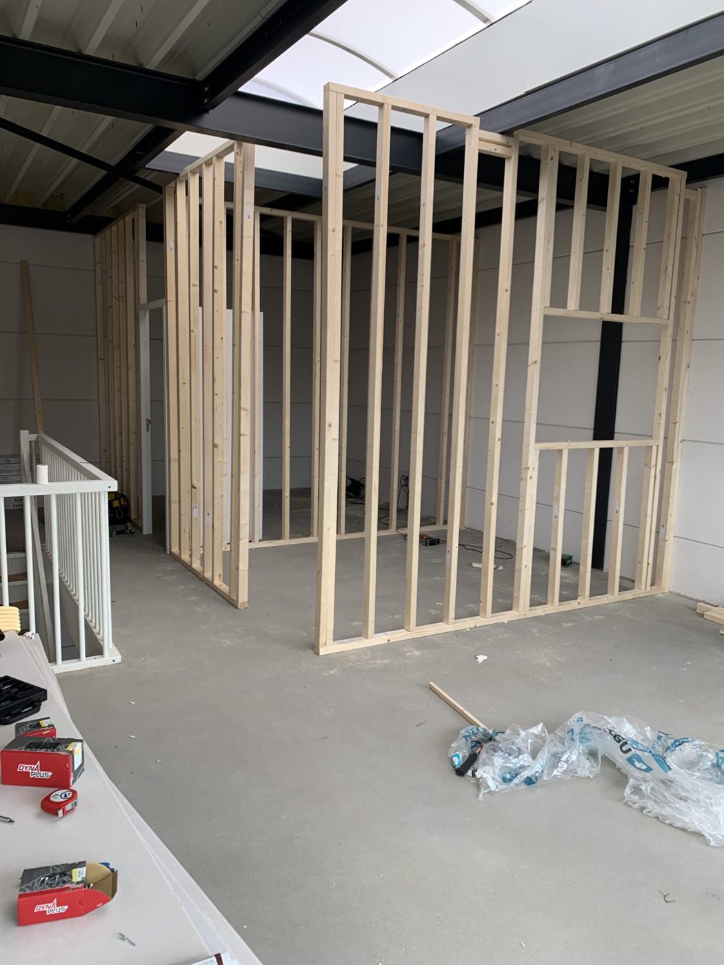 Houten frames voor nieuwe wanden tijdens de verbouwing, onder een stalen dakconstructie met lichtstraat